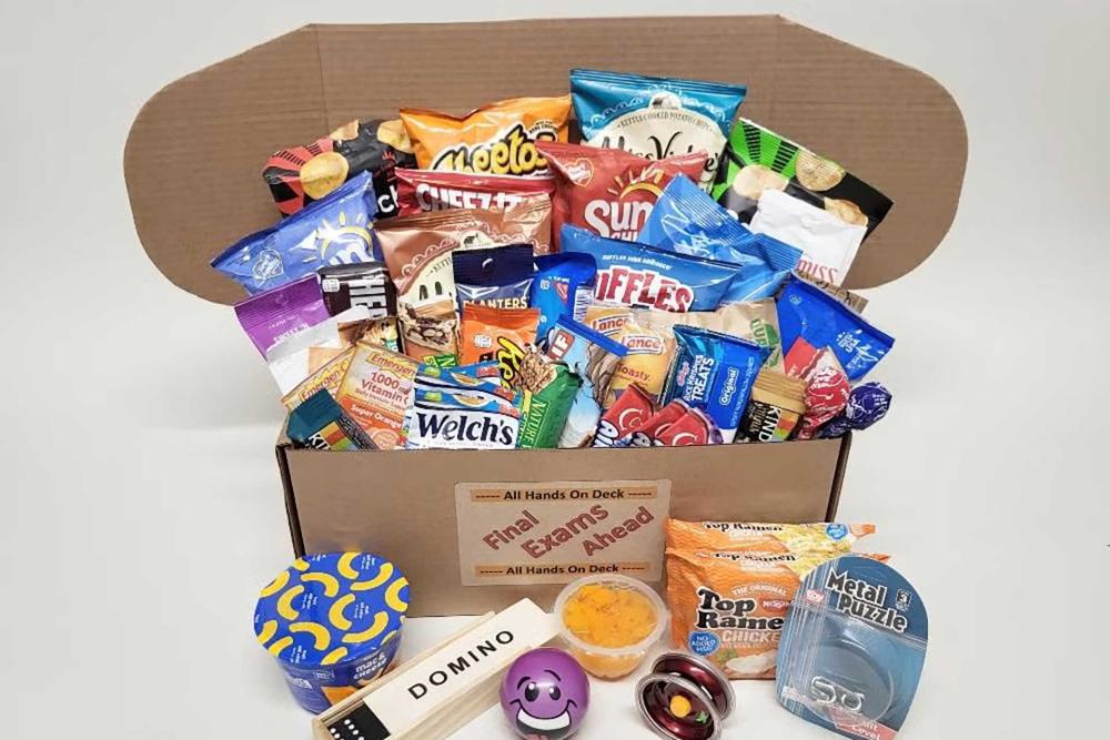 Open cardboard box overflowing with snack bags, ramen, fidget toys, and more.